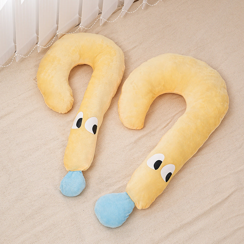 Two yellow U-shaped pillows with face designs on a beige surface