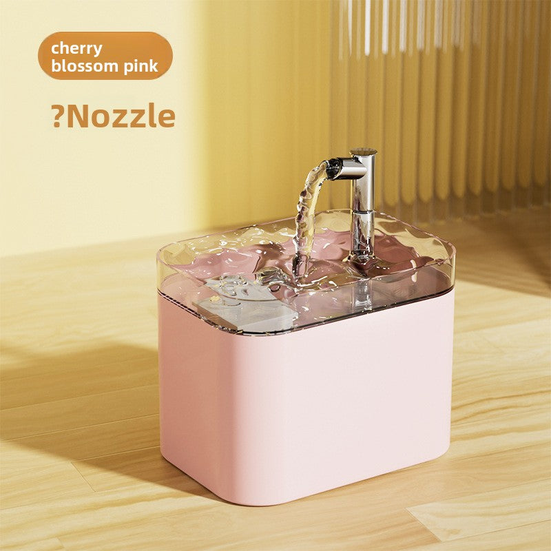 A pink pet water fountain with a clear top and a chrome faucet, shown with water flowing from the spout on a light wood floor. Text in the top left reads 'cherry blossom pink' and '?Nozzle'.