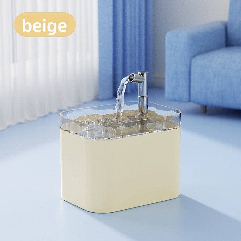 A beige rectangular water fountain with a chrome faucet and clear water spout, shown in a bright room with a blue sofa and curtains. A yellow label in the top left reads 'Beige'.