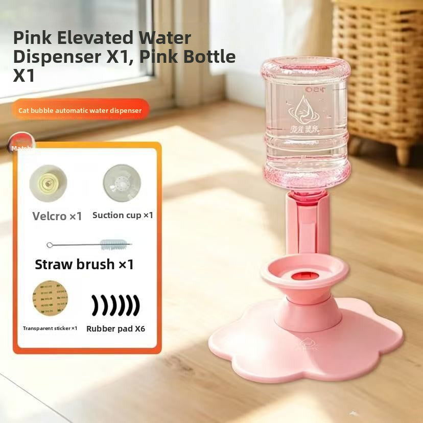 Pink elevated water dispenser with a clear bottle and pink base, shown on a wooden floor in a bright room. Text at top reads 'Pink Elevated Water Dispenser X1, Pink Bottle X1' and a product components inset on the left lists parts like suction cup, straw brush, and rubber pad.